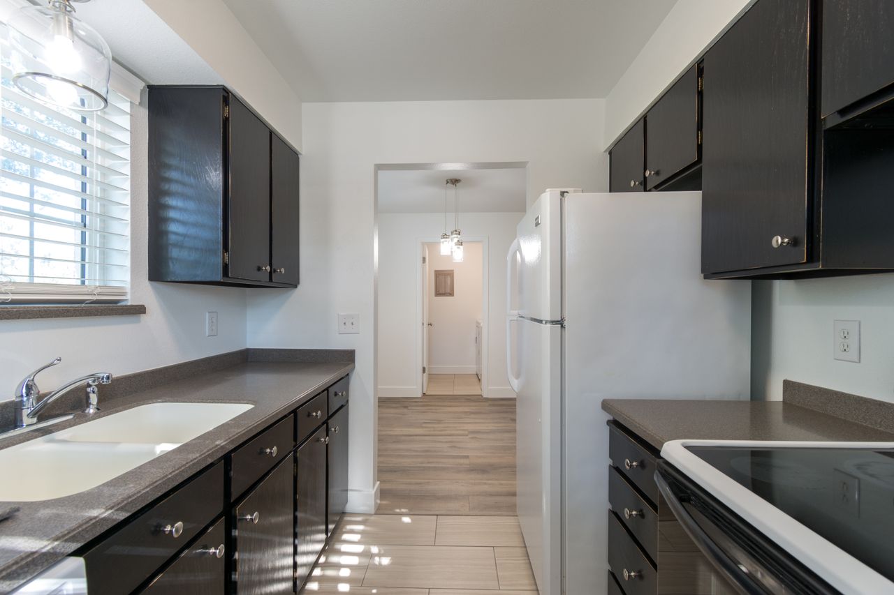 embark Contemporary kitchen design featuring dark cabinets, countertops, and white appliances for a sleek look.
